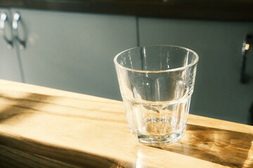 A faceted transparent glass on a tabletop in a coffee shop, with the sun's rays shining through it and reflecting