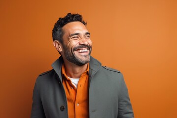 portrait of a confident Mexican man in his 30s wearing a chic cardigan against an abstract background