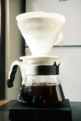 Freshly poured black coffee through a V-60 dripper in a shiny glass decanter