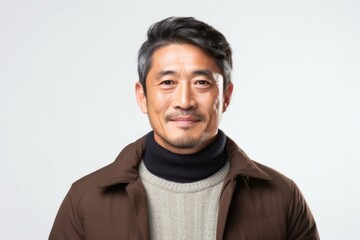 Obraz premium portrait of a serious, Japanese man in his 40s wearing a chic cardigan against a white background