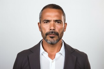 portrait of a serious, Mexican man in his 40s wearing a chic cardigan against a white background