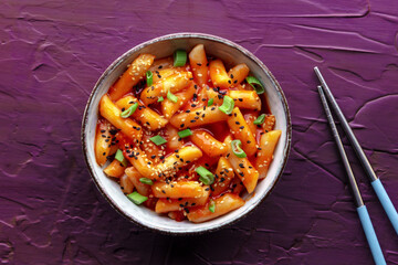 Tteokbokki or topokki, Korean street food, spicy rice cakes in red pepper gochujang sauce, overhead flat lay shot with chopsticks