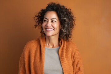 Fototapeta premium Portrait of a Mexican woman in her 50s wearing a cozy sweater against an abstract background