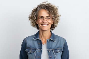 Portrait of a confident Israeli woman in her 50s wearing a denim jacket against a white background - obrazy, fototapety, plakaty