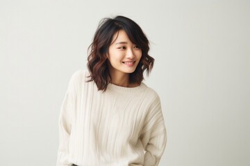 Obraz premium Portrait of a confident Japanese woman in her 30s wearing a cozy sweater against a minimalist or empty room background