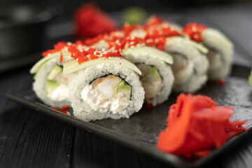 Sushi roll with caviar tobico, avocado and cream cheese on black background. Sushi menu. Japanese food concept.