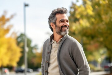 Portrait of a confident Mexican man in his 40s wearing a chic cardigan against a white background