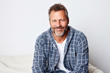 Portrait of a confident Polish man in his 40s wearing a snuggly pajama set against a white background