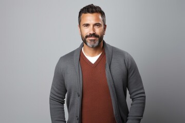 Fototapeta premium Portrait of a serious, Mexican man in his 40s wearing a chic cardigan against a white background