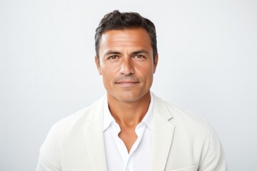 Portrait of a serious, Mexican man in his 40s wearing a chic cardigan against a white background
