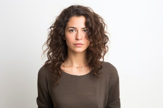 Portrait of a serious, Israeli woman in her 20s wearing a chic cardigan against a white background