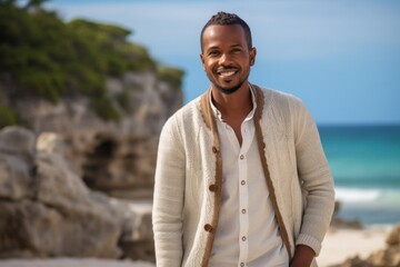 Portrait of a Kenyan man in his 30s wearing a chic cardigan against a beach background