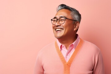 Obraz premium portrait of a happy Filipino man in his 50s wearing a chic cardigan against a pastel or soft colors background