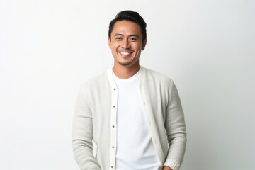 medium shot portrait of a happy Filipino man in his 30s wearing a chic cardigan against a white background - obrazy, fototapety, plakaty