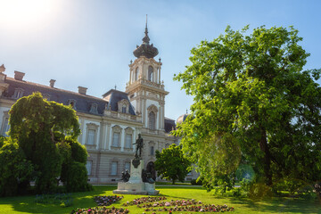Festetics Palace with beautiful garden on sunny summer day, baroque architecture, Keszthely, Zala, Hungary. Outdoor travel background with green trees and grass, and blue sky