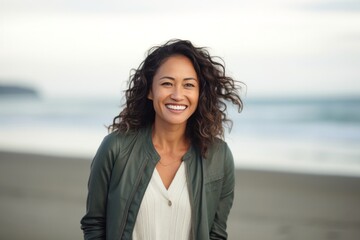 portrait of a happy Filipino woman in her 40s wearing a chic cardigan against a beach background