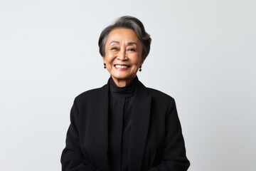 portrait of a happy Filipino woman in her 70s wearing a sleek suit against a white background