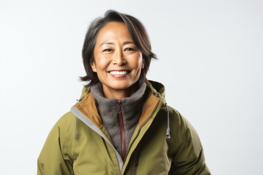 portrait of a happy Filipino woman in her 50s wearing a warm parka against a white background
