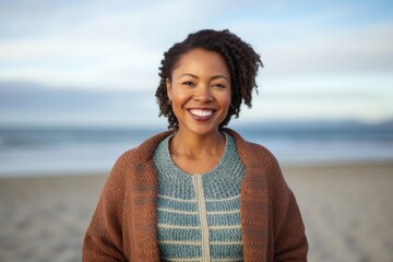 medium shot portrait of a happy Kenyan woman in her 30s wearing a chic cardigan against a beach background