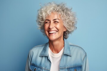 portrait of a happy Israeli woman in her 60s wearing a denim jacket against a pastel or soft colors background