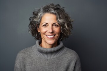 portrait of a happy Israeli woman in her 50s wearing a cozy sweater against an abstract background - obrazy, fototapety, plakaty