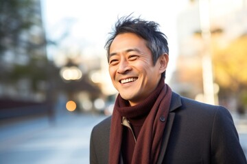portrait of a happy Japanese man in his 40s wearing a chic cardigan against an abstract background
