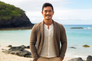 medium shot portrait of a Filipino man in his 30s wearing a chic cardigan against a beach background