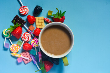 Flat lay a cup of coffee and chocolate, candies and cotton candy as a frame
