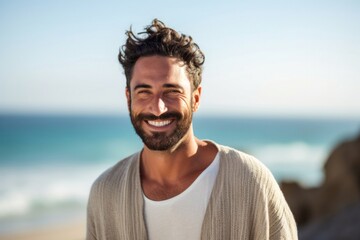 medium shot portrait of a Israeli man in his 30s wearing a chic cardigan against a beach background