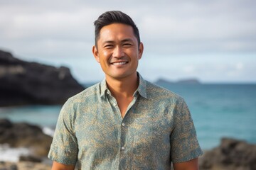 portrait of a Filipino man in his 40s wearing a chic cardigan against a beach background