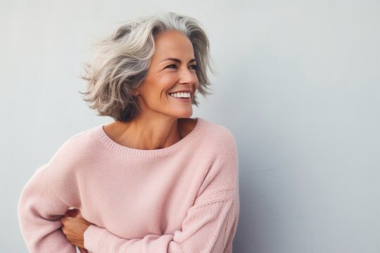 portrait of a Israeli woman in her 50s wearing a cozy sweater against a pastel or soft colors background