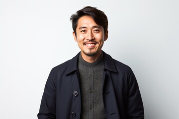 portrait of a Japanese man in his 30s wearing a chic cardigan against a white background