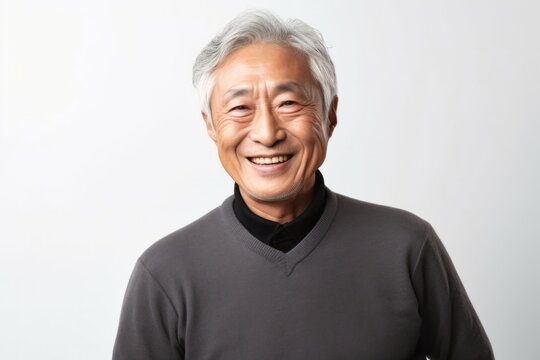portrait of a Japanese man in his 70s wearing a chic cardigan against a white background