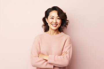 Fototapeta premium portrait of a Japanese woman in her 40s wearing a cozy sweater against a pastel or soft colors background