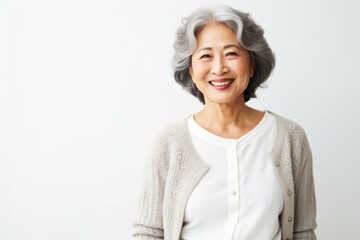 portrait of a Japanese woman in her 50s wearing a chic cardigan against a white background