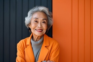 medium shot portrait of a confident Filipino woman in her 90s wearing a classic blazer against an abstract background