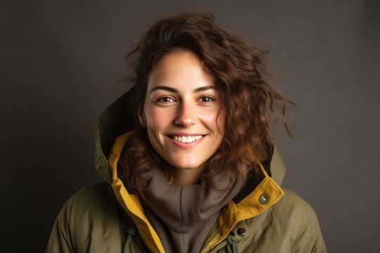 medium shot portrait of a confident Israeli woman in her 30s wearing a warm parka against an abstract background