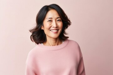 medium shot portrait of a confident Japanese woman in her 40s wearing a cozy sweater against a pastel or soft colors background