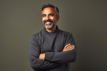 Fototapeta premium portrait of a Mexican man in his 50s wearing a chic cardigan against a minimalist or empty room background