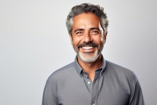 portrait of a Mexican man in his 50s wearing a chic cardigan against a white background