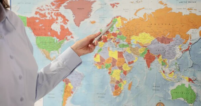 Woman points to world map in class. Logistic services and delivery of goods around the world