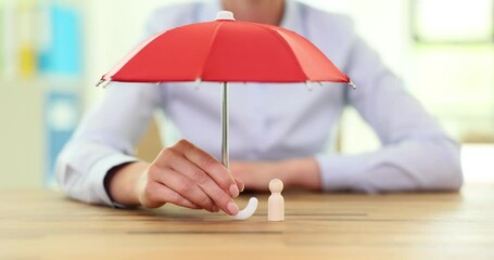Red umbrella with peg doll to protect the wooden doll. Risk and crisis prevention and healthcare and insurance