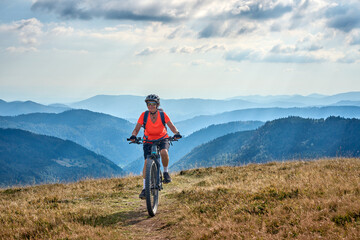 nice senior woman on her electric mountain bike cycling on Feldberg summit with stunning view over...