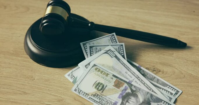 Judge gavel, money and hand for bribe on table or auction, corruption and court expense. Dollar bill, finance and mallet for laundering, currency or law attorney for fraud, debt or government scam