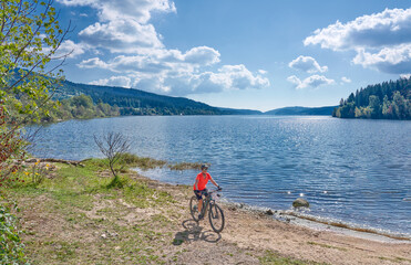 nice senior woman on her electric mountain bike cycling at Lake Schluchsee in the German Black...