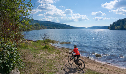 nice senior woman on her electric mountain bike cycling at Lake Schluchsee in the German Black...