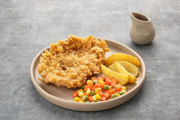 Crispy Chicken Steak with french fries and vegetables. 
