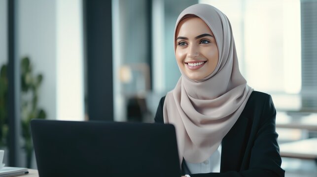 Young Muslim woman wearing a hijab is working on a laptop in the office