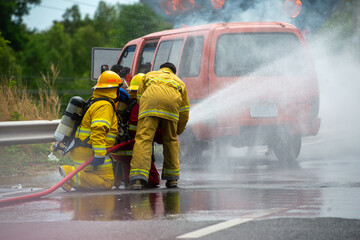 Firefighters are spraying high-pressure water to extinguish a fire caused by a car crash.