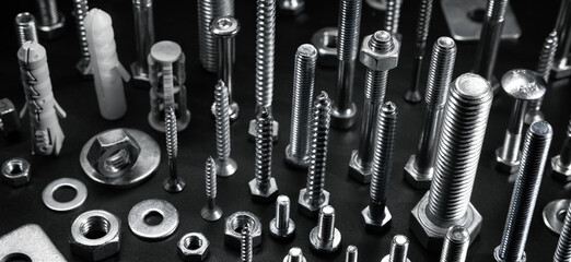 various metal screws, bolts and fasteners on black background - obrazy, fototapety, plakaty